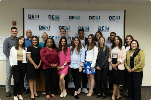 Group of professionals posing in front of a DE&I (Diversity, Equity & Inclusion) banner.